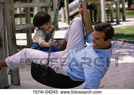 Stock Image - Side profile of a father and his son playing on a tire swing. Fotosearch