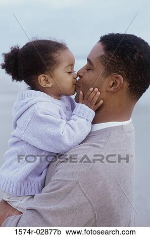 Stock Image - Side profile of a father kissing his daughter. Fotosearch