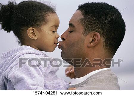 Stock Image - Side profile of a father kissing his daughter. Fotosearch