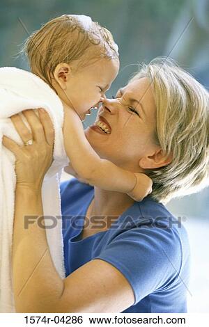 Stock Photograph - Side profile of a mother lifting her baby boy nuzzling. Fotosearch