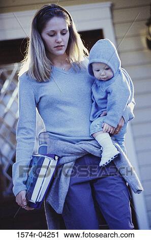 Stock Image - Teenage girl carrying her baby boy and books. Fotosearch