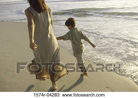 Young woman walking with her son on the beach View Large Photo Image Stock Image - Young woman walking with her son on the beach. Fotosearch