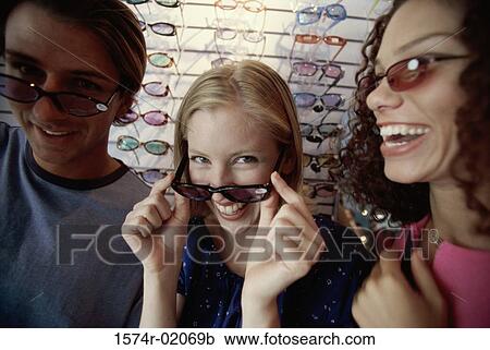 Stock Image - Close-up of a young man and two young women wearing sunglasses. Fotosearch