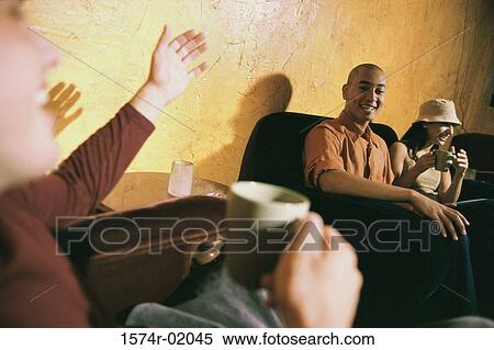 Close-up of a young man talking to friends in a living room View Large Photo Image Stock Photography - Close-up of a young man talking to friends in a living room. Fotosearch
