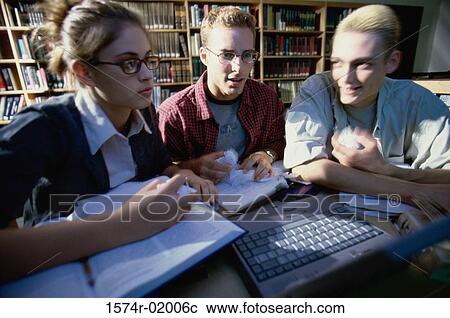 Stock Image - Close-up of three teenage students studying in a library. Fotosearch