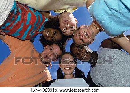 Low angle view of young men and women in a huddle View Large Photo Image Stock Image - Low angle view of young men and women in a huddle. Fotosearch