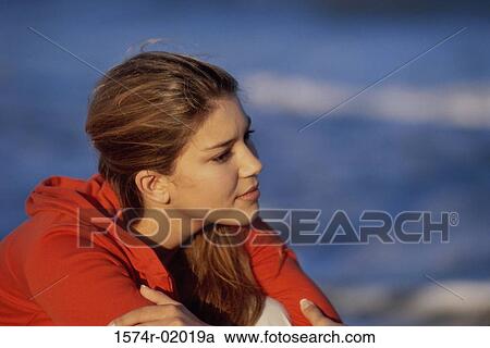 Stock Image - Side profile of a teenage girl sitting at the beach. Fotosearch