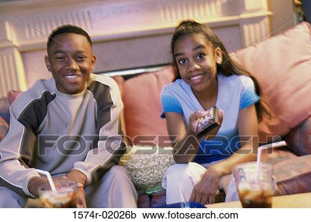 Teenage boy and girl sitting on a couch and watching television View Large Photo Image Stock Image - Teenage boy and girl sitting on a couch and watching television. Fotosearch