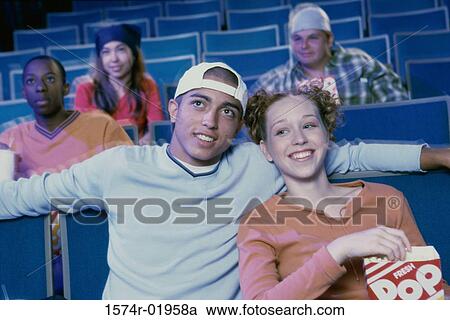 Stock Image - Teenage couple watching a movie in a theater. Fotosearch