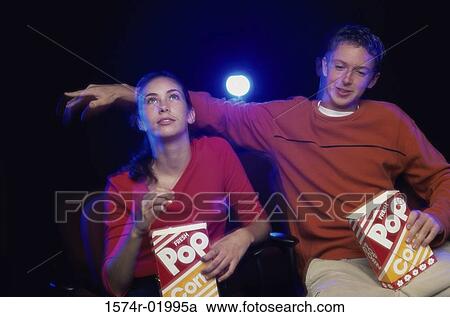 Stock Image - Teenage couple watching a movie in a theater. Fotosearch