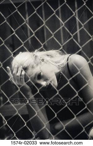 Teenage girl sitting behind a chain-link fence View Large Photo Image Stock Image - Teenage girl sitting behind a chain-link fence. Fotosearch