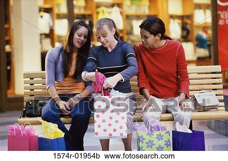 Three teenage girls looking at clothes in shopping bags View Large Photo Image Stock Image - Three teenage girls looking at clothes in shopping bags. Fotosearch