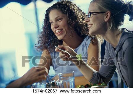 Two young women eating in a cafe with an unrecognized person View Large Photo Image Stock Photo - Two young women eating in a cafe with an unrecognized person. Fotosearch