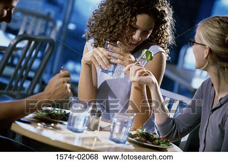 Two young women eating in a cafe with an unrecognized person View Large Photo Image Stock Photo - Two young women eating in a cafe with an unrecognized person. Fotosearch