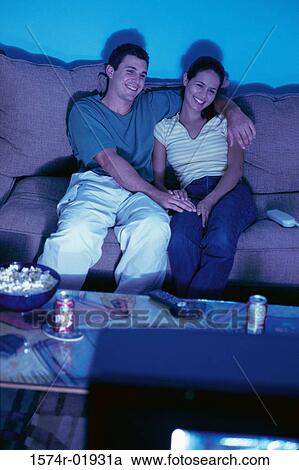 Stock Image - Young couple sitting on a couch and watching television. Fotosearch