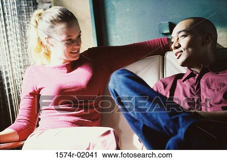 Young couple sitting on a couch View Large Photo Image Stock Image - Young couple sitting on a couch. Fotosearch