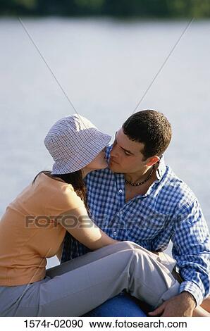 Young couple sitting outdoors kissing View Large Photo Image Stock Image - Young couple sitting outdoors kissing. Fotosearch