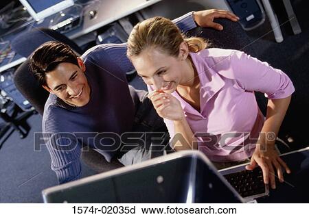 Young man and a young woman looking at a computer monitor View Large Photo Image Stock Image - Young man and a young woman looking at a computer monitor. Fotosearch