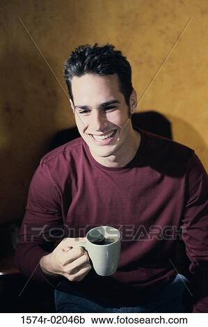 Stock Image - Young man holding a cup of coffee. Fotosearch