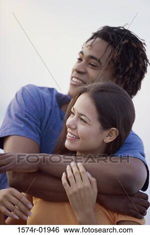 Young man holding a young woman from behind View Large Photo Image Stock Photograph - Young man holding a young woman from behind. Fotosearch
