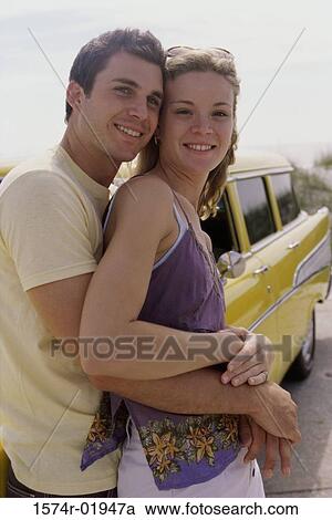 Young man leaning against a car holding a young woman from behind View Large Photo Image Stock Image - Young man leaning against a car holding a young woman from behind. Fotosearch