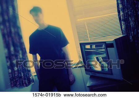 Young man standing beside a television View Large Photo Image Stock Image - Young man standing beside a television. Fotosearch