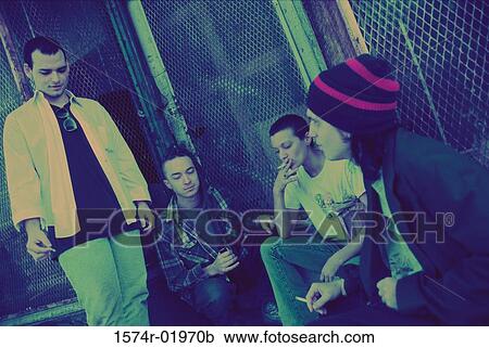 Young men and women smoking on a sidewalk View Large Photo Image Stock Image - Young men and women smoking on a sidewalk. Fotosearch