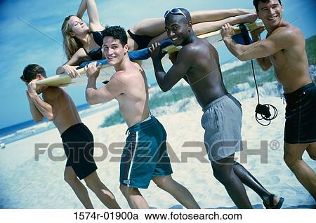 Young men carrying a woman on a surfboard View Large Photo Image Stock Image - Young men carrying a woman on a surfboard. Fotosearch