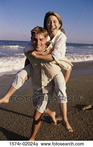 Young woman riding piggyback on a young man at the beach View Large Photo Image Stock Image - Young woman riding piggyback on a young man at the beach. Fotosearch