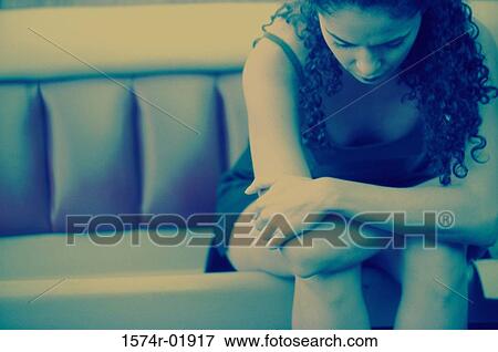 Young woman sitting on a couch with her head down View Large Photo Image Stock Photo - Young woman sitting on a couch with her head down. Fotosearch