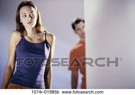 Young woman standing with a young man behind her View Large Photo Image Stock Image - Young woman standing with a young man behind her. Fotosearch
