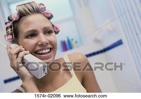 Stock Photograph - Young woman with curlers in her hair talking on a telephone. Fotosearch