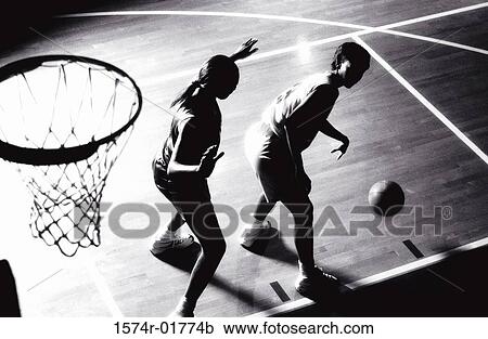 Stock Image - High angle view of two women playing basketball. Fotosearch