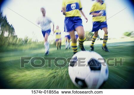 Stock Image - Low angle view of a girls soccer team playing soccer on a field. Fotosearch