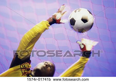 Stock Image - Low angle view of a goalie catching a ball. Fotosearch
