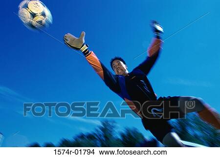 Picture - Low angle view of a teenage goalie reaching for the ball. Fotosearch