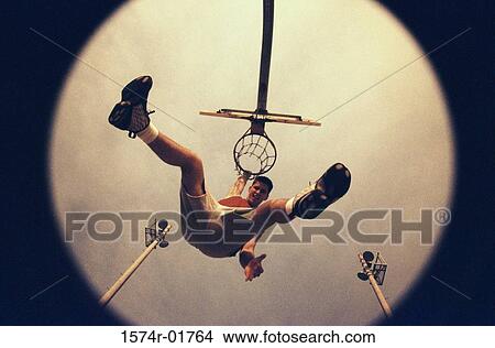 Low angle view of a young male basketball player hanging from the hoop View Large Photo Image Picture - Low angle view of a young male basketball player hanging from the hoop. Fotosearch