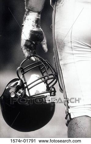 Stock Image - Low angle view of an American football player holding a helmet. Fotosearch