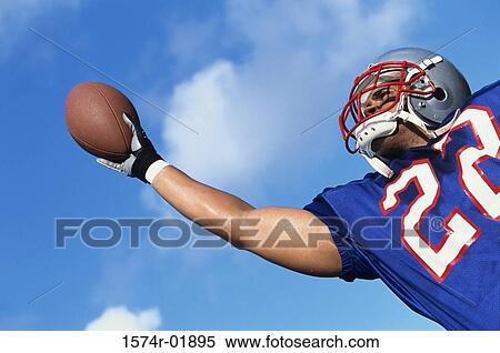 Stock Photography - Low angle view of an American football player catching a ball. Fotosearch