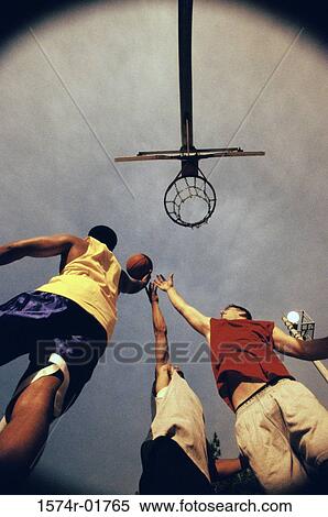 Stock Photography - Low angle view of three young men playing basketball. Fotosearch