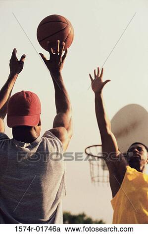 Stock Image - Low angle view of two men playing basketball. Fotosearch