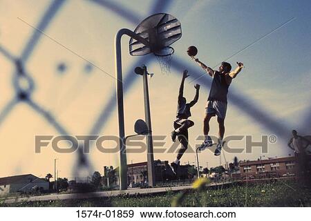 Stock Photo - Low angle view of two men playing basketball. Fotosearch