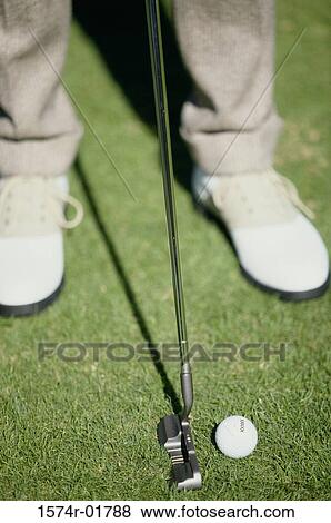 Stock Photo - Low section view of a man putting a golf ball. Fotosearch