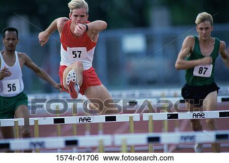 Male runners jumping hurdles in a race View Large Photo Image Stock Photograph - Male runners jumping hurdles in a race. Fotosearch