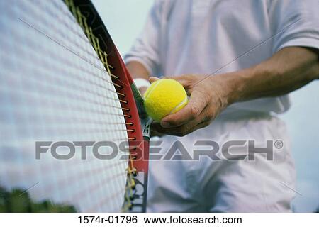 Stock Photograph - Man holding a tennis ball and a tennis racket. Fotosearch