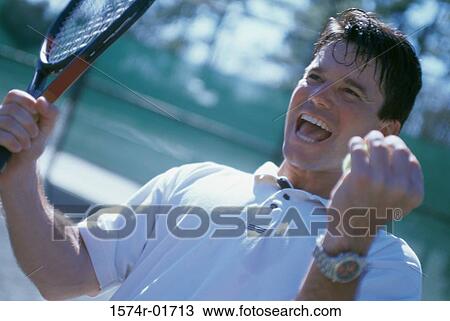 Mid adult man holding a tennis racket raising his hands in excitement View Large Photo Image Stock Image - Mid adult man holding a tennis racket raising his hands in excitement. Fotosearch