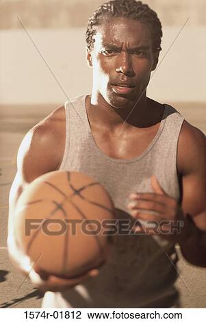 Stock Image - Portrait of a basketball player holding a ball. Fotosearch