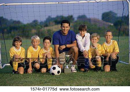 Stock Image - Portrait of a soccer team and coach on a field with a trophy. Fotosearch