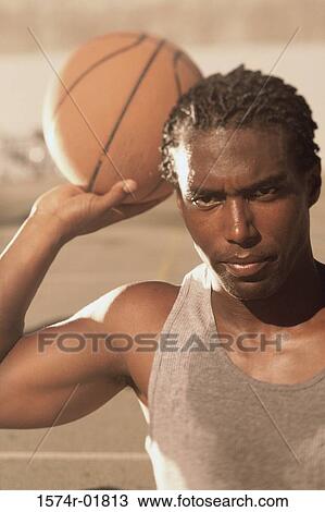 Stock Image - Portrait of a young man holding a basketball. Fotosearch