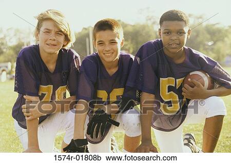 Stock Image - Portrait of three boys holding a football. Fotosearch